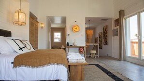 Een slaapkamer met een bed, nachtkastje en uitzicht.
