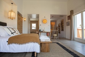 Een slaapkamer met een bed, nachtkastje en uitzicht.