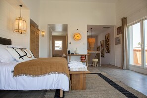 Een slaapkamer met een bed, nachtkastje en uitzicht.