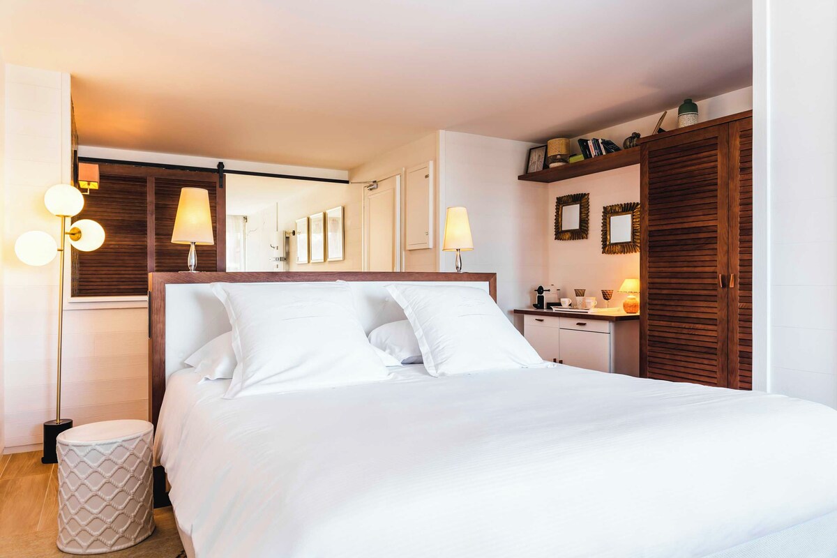 Une chambre à coucher bien rangée, avec un lit, des lampes de chevet, une table de chevet et une armoire.