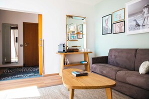 A living room with a brown sofa, a wooden coffee table, a mirror, and framed pictures on the wall. - Relais et Châteaux Ile de la Lagune (Saint-Cyprien)