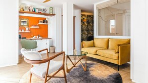 Ein modernes Wohnzimmer mit einem gelben Sofa, einem Glastisch und einem Holzsessel.