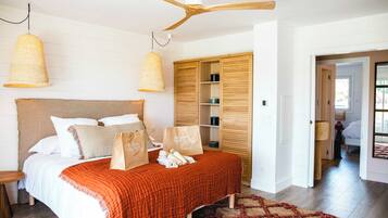 A bedroom with a bed, wooden wardrobe, ceiling fan, and hanging lamps.