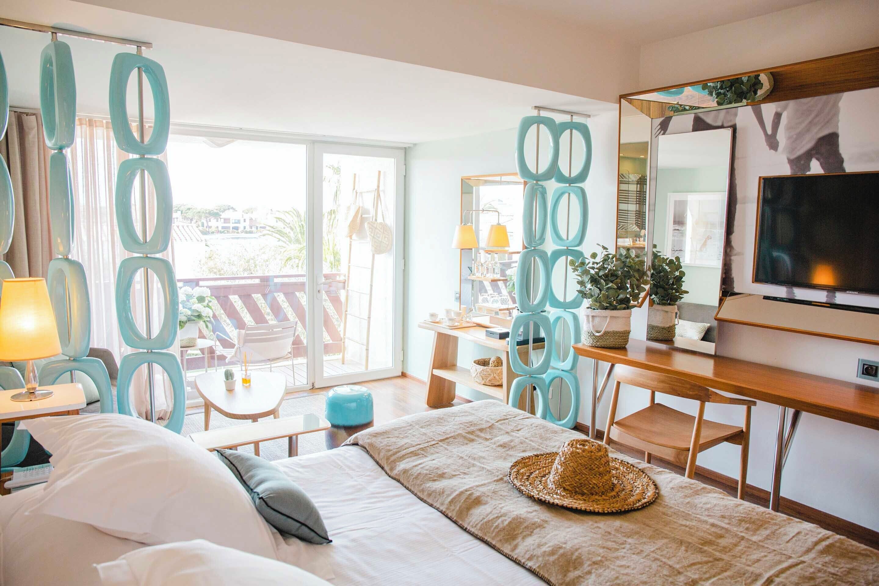 Habitació d'hotel amb llit, escriptori, televisió i un balcó amb cadires i taula.