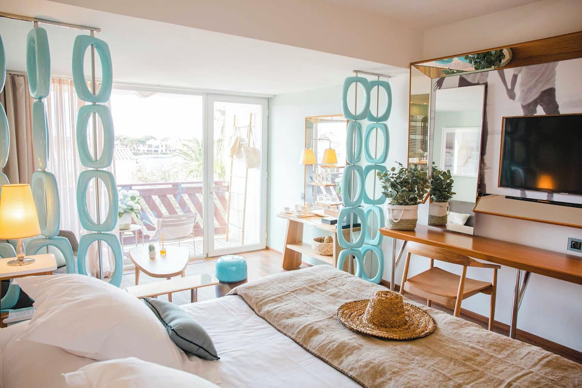 Ein Hotelzimmer mit Bett, Schreibtisch, Fernseher und einem Balkon mit Stühlen und Tisch.