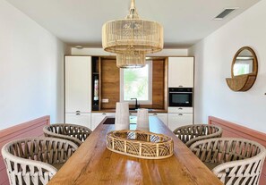 Een moderne keuken met witte kasten, een inbouwoven en een raam met uitzicht op groen.