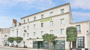 Un hôtel-chambre d’hôtes à la façade classique, doté de nombreuses fenêtres et d’un petit arbre devant l’entrée.