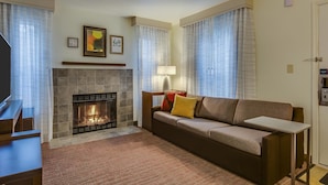 A living room with a fireplace, a sofa, a coffee table, and curtains. - Residence Inn By Marriott South Bend (South Bend)