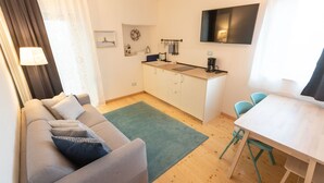 Un espacio habitable compacto con sofá, mesa de comedor y kitchenette.