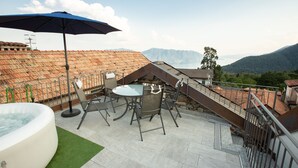 Terraza en la azotea con hidromasaje, mobiliario exterior y vistas a montañas.