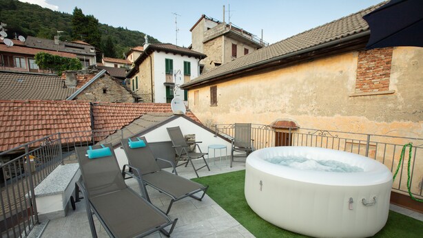 Un patio exterior con sillones de descanso, una bañera de hidromasaje y vistas de edificios circundantes.