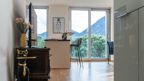 A modern kitchen with a wooden countertop, a black dog figurine, a vase with flowers, and a large window offering a mountain view.