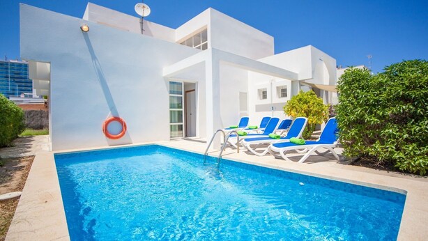 Un hotel moderno con piscina, sillas de descanso azules y un flotador.