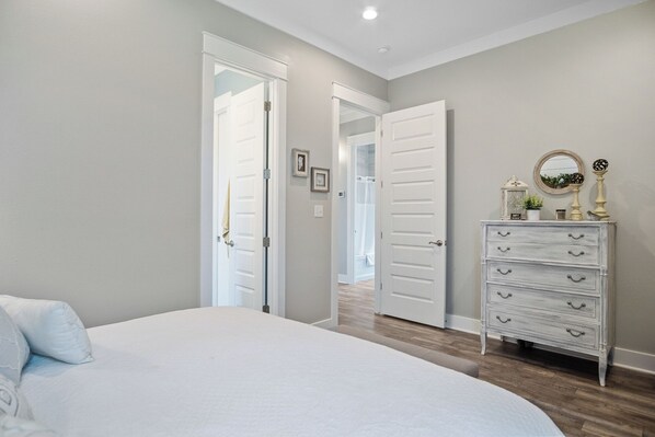 Un dormitorio con cama, cómoda y puerta que da a otra habitación.