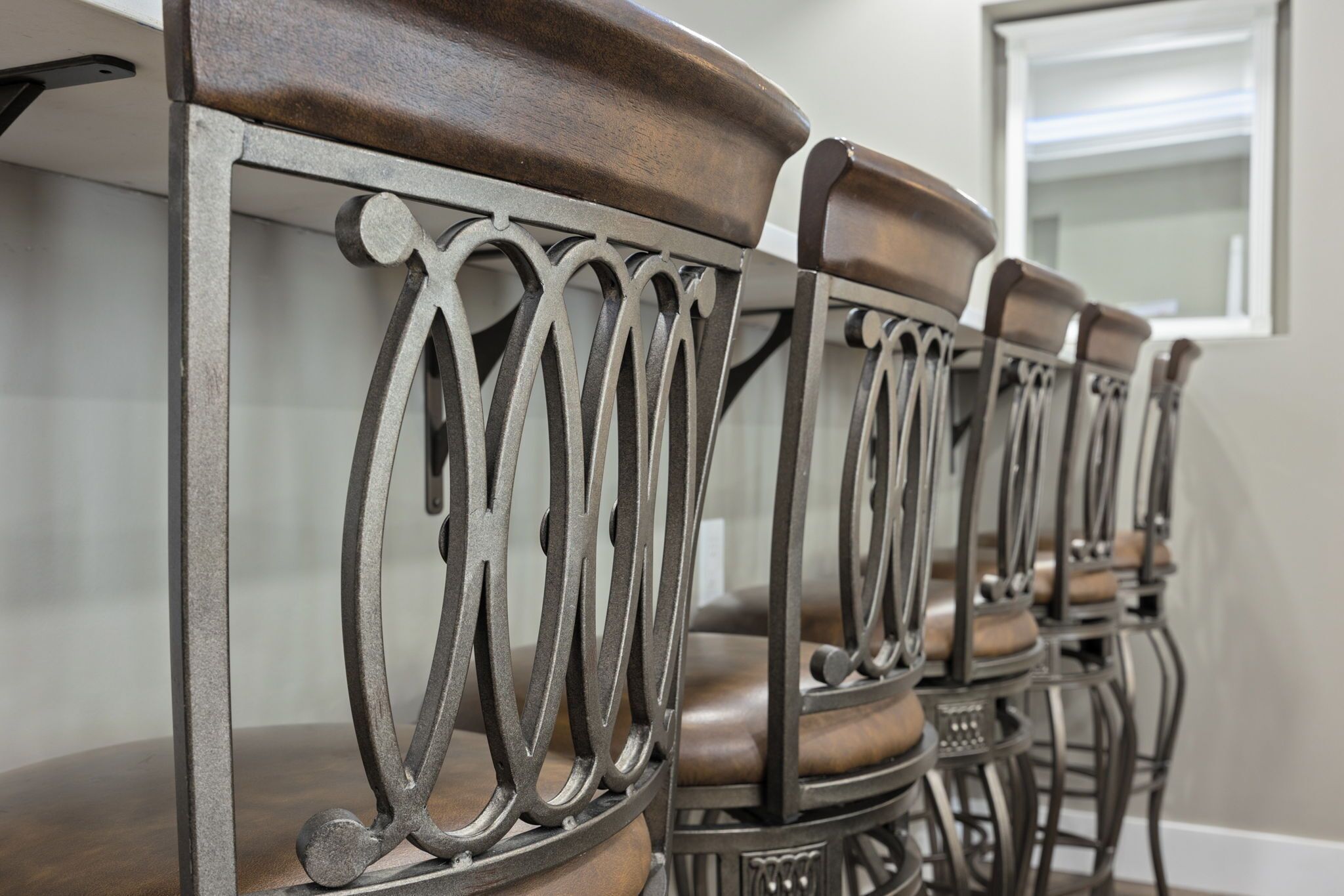 A row of dining chairs with ornate metal backrests and cushioned seats.