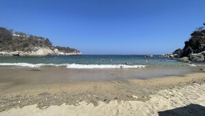 A beach with clear blue water, rocky cliffs, and a sandy shore. - Oceanview Punta Arrocito Luxury Condo, Near Arrocito Beach (Huatulco)