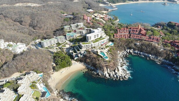 An aerial view of a coastal resort with multiple buildings, a beach, and a rocky shoreline. - Oceanview Punta Arrocito Luxury Condo, Near Arrocito Beach (Huatulco)