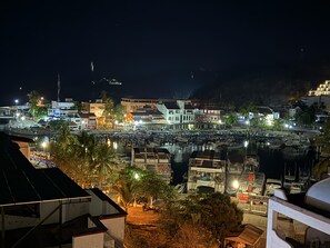 A nighttime view of a coastal town with buildings, a marina, and boats.
