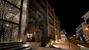 Een meerlaags hotel met een moderne gevel, buitenverlichting en een trap die naar de ingang leidt.