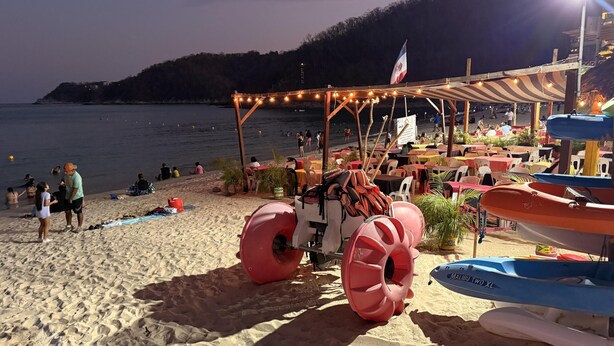 Ein Restaurant am Strand mit Terrassensitzplätzen, einer Flagge und Blick aufs Meer.