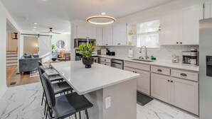 A modern kitchen with white cabinets, a central island, and a pendant light.