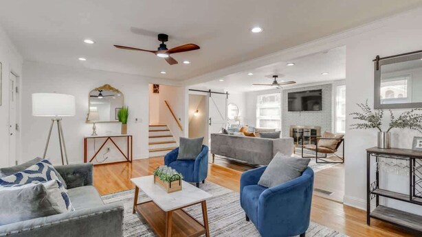 A modern living room with a grey sofa, blue armchairs, a coffee table, and a staircase leading to another level.