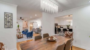 A spacious dining area with a wooden table, blue chairs, and a chandelier.