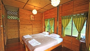 A wooden cabin room with a bed, a window with curtains, and a hanging light fixture. - River Kwai Jungle View (Sai Yok)