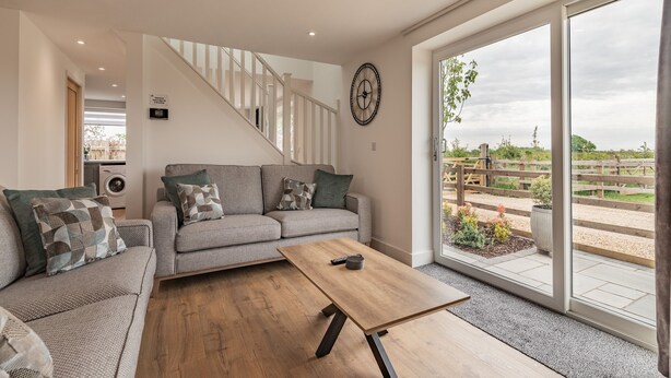 A modern living room with a sofa, coffee table, and a staircase leading to another level. - 3 bedroom accommodation in Church Broughton, near Derby (Church Broughton, near Derby)