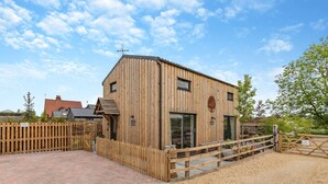 A wooden building with a sloped roof, a wooden fence, and a gravel driveway. - 3 bedroom accommodation in Church Broughton, near Derby (Church Broughton, near Derby)