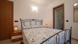 A bedroom with a bed, wooden wardrobe, bedside lamps, and a mirror. - Apartment Luna with Pool (Nerano)