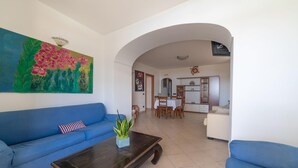 A living room with a blue sofa, a coffee table, and a painting of flowers. - Apartment Luna with Pool (Nerano)