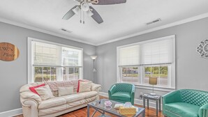 A living room with a beige leather sofa, a green armchair, a glass coffee table, and a ceiling fan. - ReNew At JW's & bring your Dog too! (Florence)
