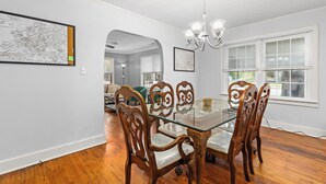 A dining area with a glass-top table, wooden chairs, and a chandelier. - ReNew At JW's & bring your Dog too! (Florence)