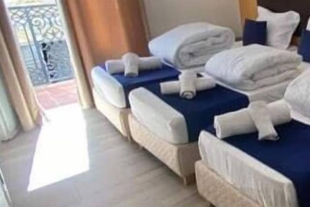 A hotel room with multiple beds, each with white linens and blue bedspreads.