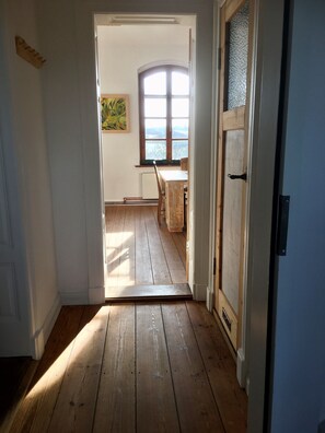 Un pasillo que conduce a un comedor con suelo de madera, una ventana con vistas y un cuadro en la pared.