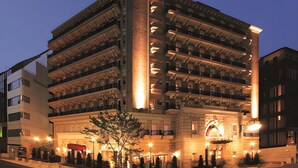Un hotel de varios pisos con un patio central, balcones en cada planta y una entrada destacada con toldo.