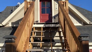 A wooden staircase leading to a red door with a mailbox on the right. - S Broadway 2 bed getaway w Parking - 98 walk score (Denver)