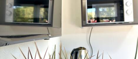 A kitchen with a microwave and a kettle on the counter.