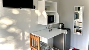 A compact kitchenette with a microwave, kettle, and a small table. - Protea Guesthouse  (Newcastle)