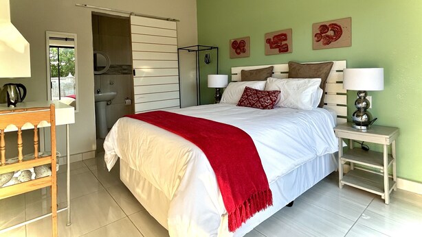 A bedroom with a bed, bedside tables, a desk, and a window. - Protea Guesthouse  (Newcastle)