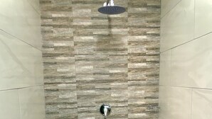 A shower with a stone wall and a handheld showerhead. - Protea Guesthouse  (Newcastle)