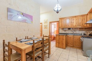 Un coin repas avec une table et des chaises en bois, une cuisine avec des meubles en bois et un lustre.