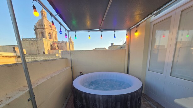 Ett bubbelbad på en takterrass med utsikt över en historisk byggnad.