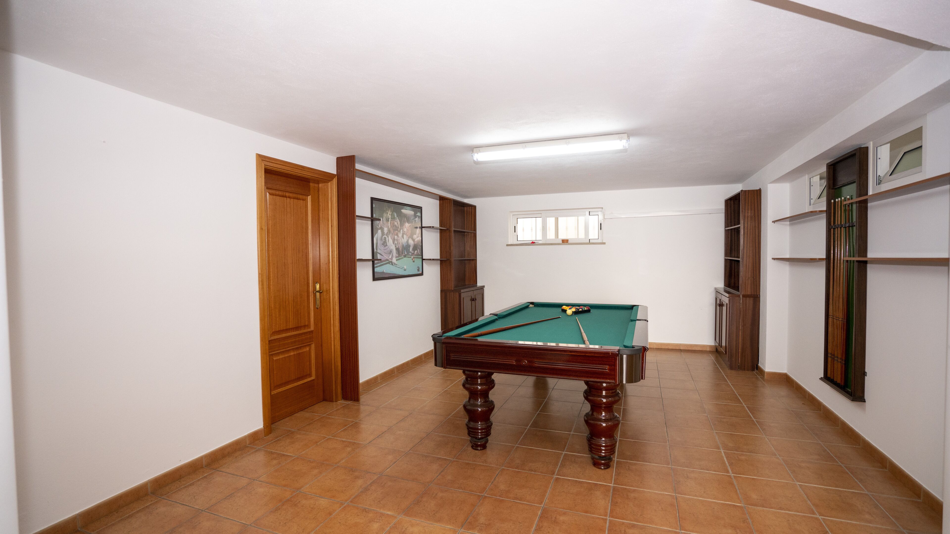A pool room with a pool table, wooden cabinets, and a door.