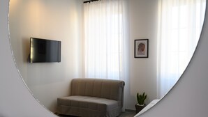 Una sala de estar moderna con un sofá, un televisor de pantalla plana montado en la pared, un cuadro enmarcado y una planta en maceta.