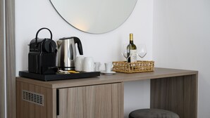 Una kitchenette con cafetera, hervidor y copa de vino sobre una encimera de madera.