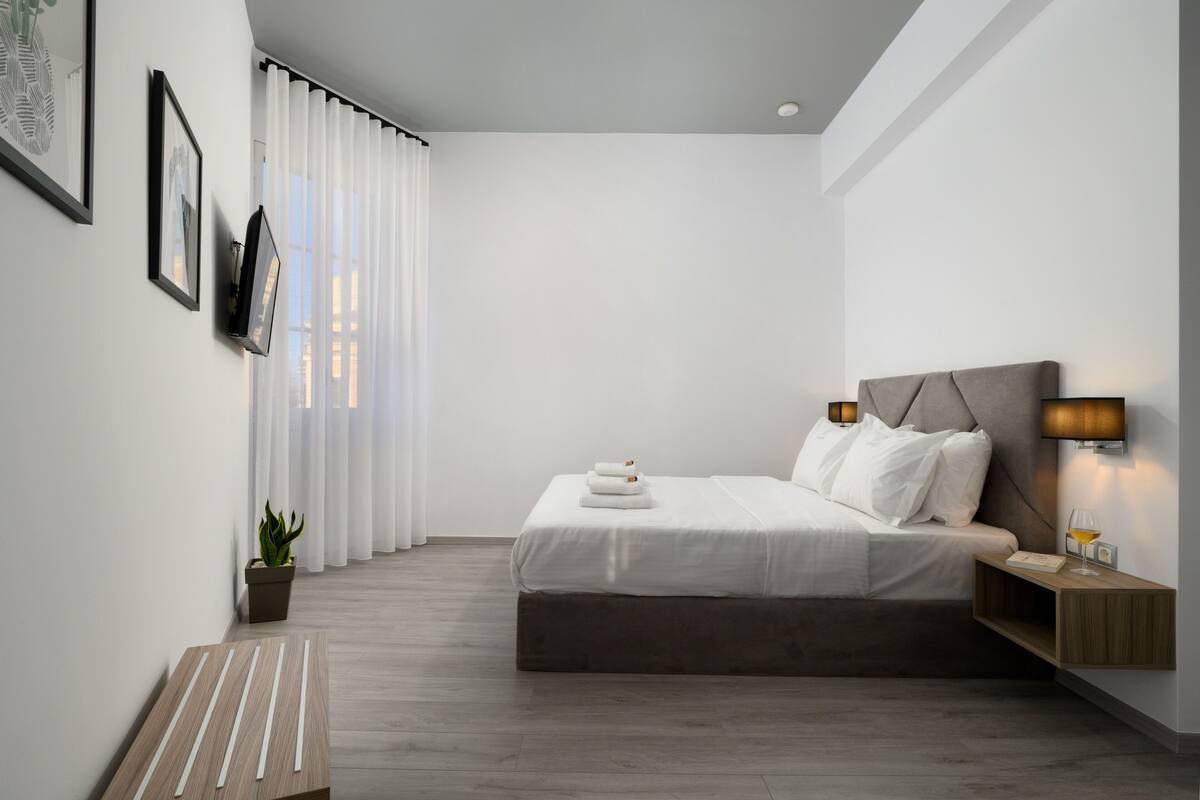Une chambre à coucher moderne avec un lit, une table de chevet, une lampe et une plante en pot.