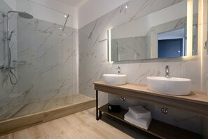 Ein modernes Badezimmer mit einer Duschkabine, zwei Waschbecken und einem großen Spiegel.