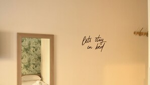 Une chambre à coucher comprenant un lit, un banc, une petite table et un miroir fixé au mur.